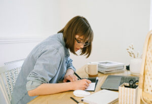 Young woman sitting at a desk and writing in a journal.