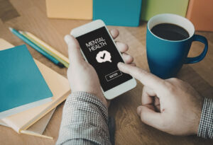 Male hands holding a smartphone with a mental health app on the screen